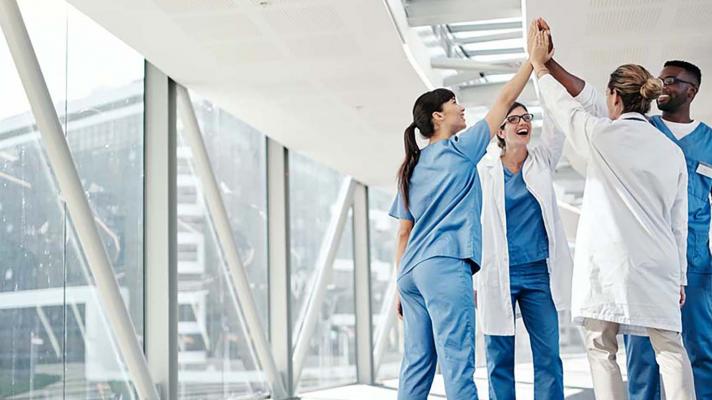 Group of healthcare workers sharing a high-five Group of healthcare workers sharing a high-five